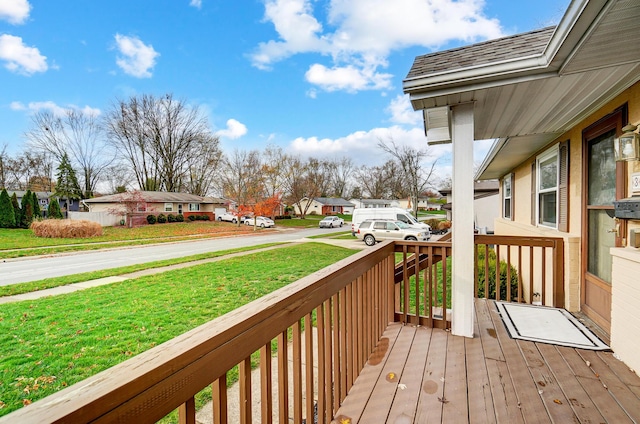 wooden terrace with a lawn and covered porch