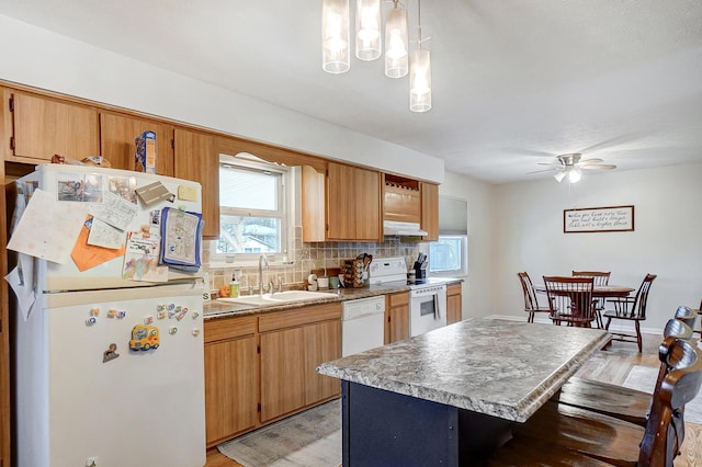 kitchen featuring sink, white appliances, a center island, decorative backsplash, and decorative light fixtures