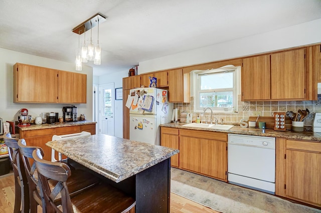 kitchen featuring sink, a kitchen breakfast bar, hanging light fixtures, a center island, and white appliances