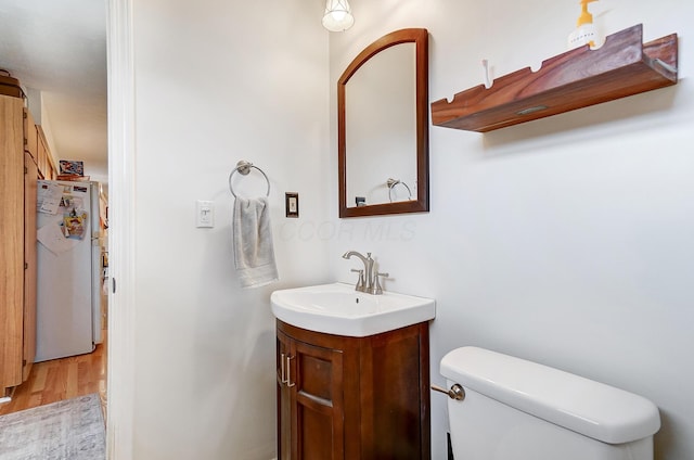 bathroom featuring vanity, hardwood / wood-style floors, and toilet