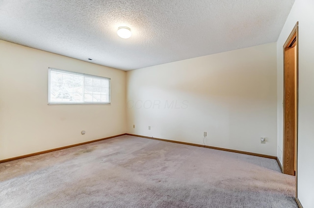 empty room with light carpet and a textured ceiling