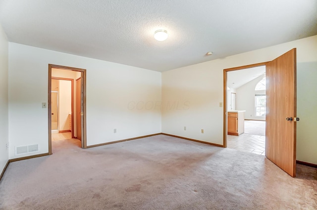 carpeted empty room featuring lofted ceiling and a textured ceiling