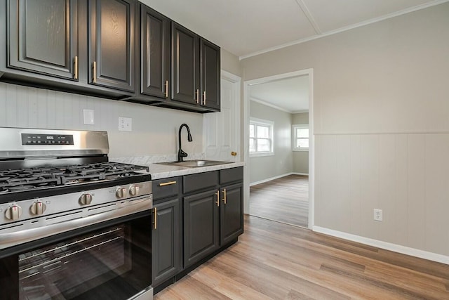 kitchen featuring crown molding, sink, gas range, and light wood-type flooring