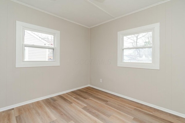 spare room with crown molding, plenty of natural light, and light wood-type flooring