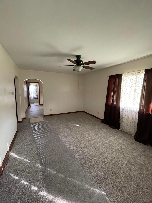 carpeted empty room with a wealth of natural light and ceiling fan