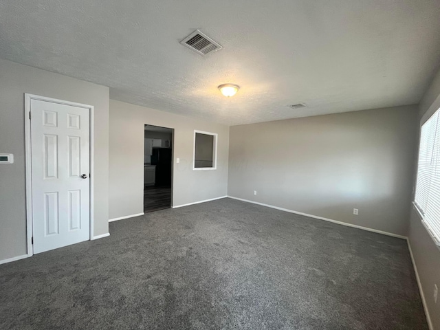 unfurnished bedroom with dark carpet and a textured ceiling