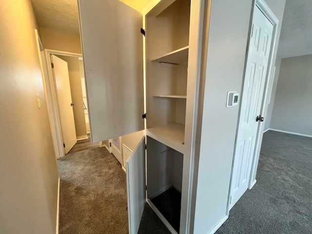 interior space with a textured ceiling and dark carpet