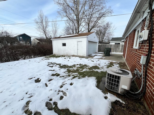 snowy yard featuring a garage, central AC, and an outdoor structure