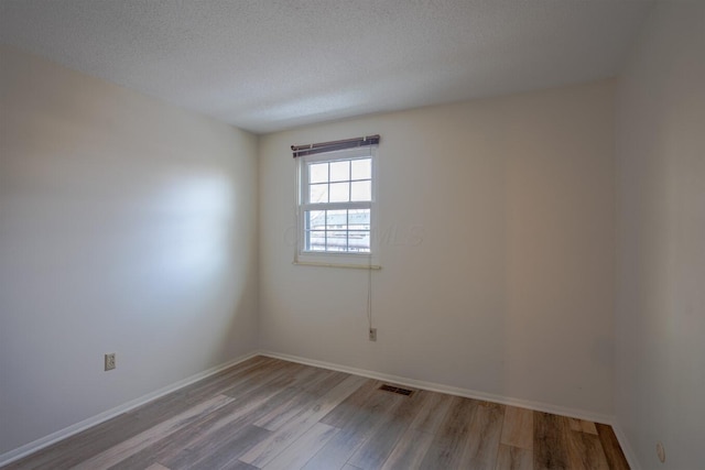 empty room with a textured ceiling and light wood-type flooring