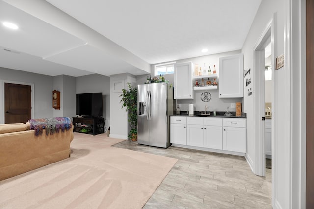 kitchen featuring light wood-type flooring, sink, stainless steel fridge with ice dispenser, and white cabinets