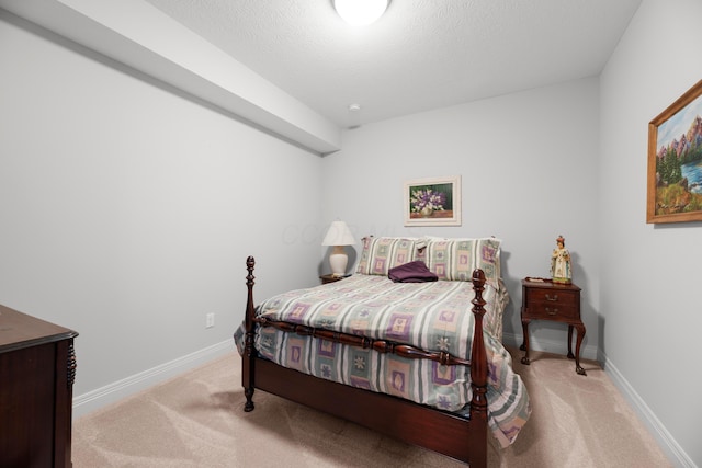 bedroom featuring light colored carpet and a textured ceiling