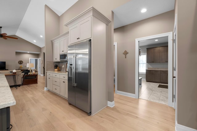 kitchen with light stone counters, light hardwood / wood-style flooring, white cabinets, and appliances with stainless steel finishes