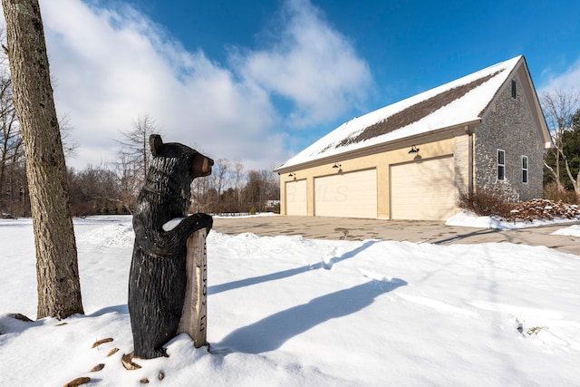 view of snowy exterior featuring a garage