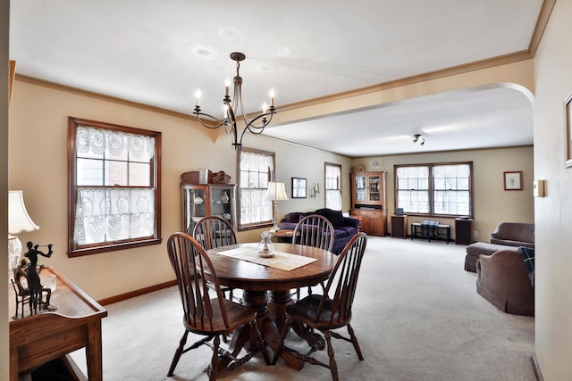 dining space with crown molding, an inviting chandelier, and light carpet