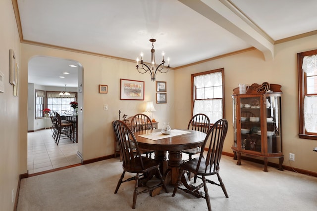 dining room featuring light carpet, ornamental molding, and an inviting chandelier