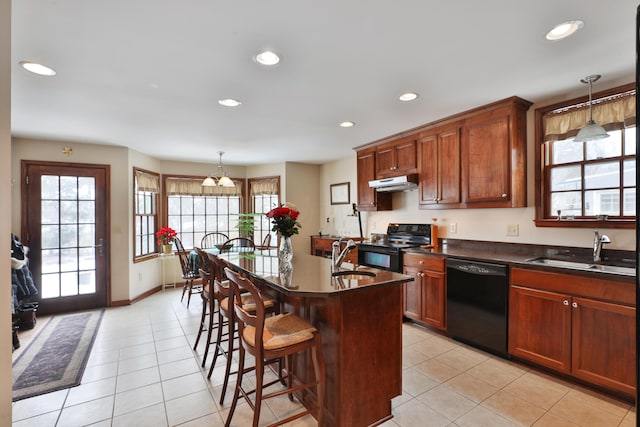 kitchen featuring pendant lighting, sink, black appliances, and an island with sink