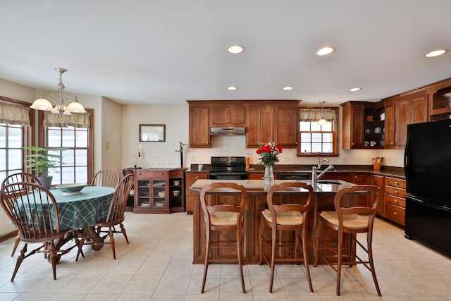 kitchen featuring a breakfast bar area, hanging light fixtures, light tile patterned floors, a notable chandelier, and black appliances