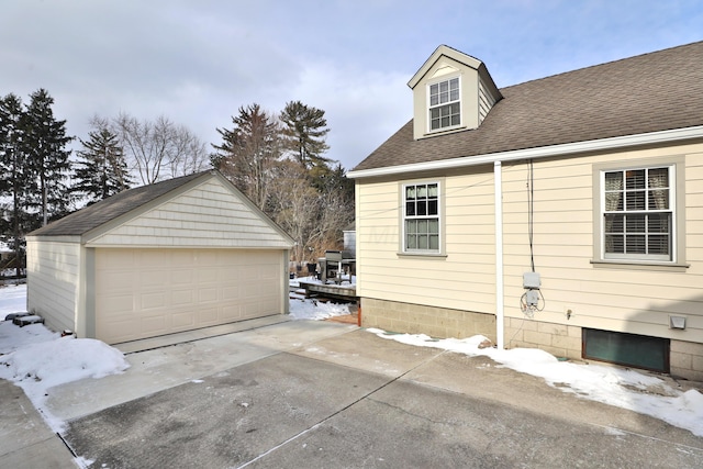 snow covered property featuring an outbuilding and a garage