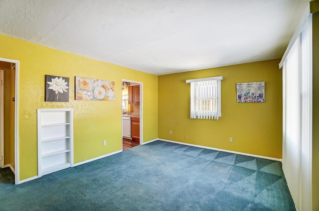 unfurnished bedroom featuring dark colored carpet, connected bathroom, and a textured ceiling