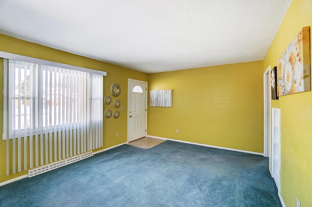 carpeted spare room with a baseboard heating unit