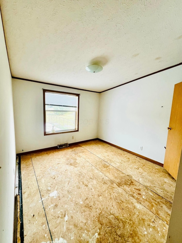 empty room featuring ornamental molding and a textured ceiling