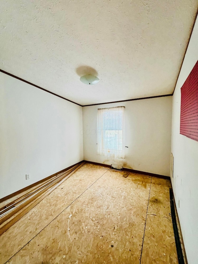 unfurnished room featuring ornamental molding and a textured ceiling