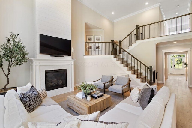 living room featuring ornamental molding, a towering ceiling, and light wood-type flooring