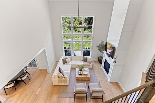 living room featuring an inviting chandelier, light wood-type flooring, and a high ceiling