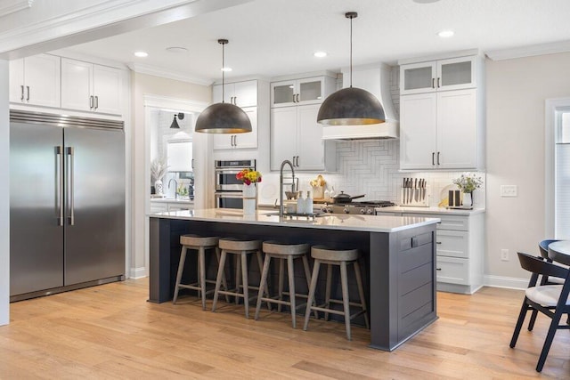 kitchen featuring pendant lighting, appliances with stainless steel finishes, a kitchen island with sink, and white cabinets