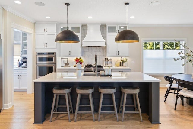 kitchen with custom exhaust hood, pendant lighting, white cabinets, and double oven