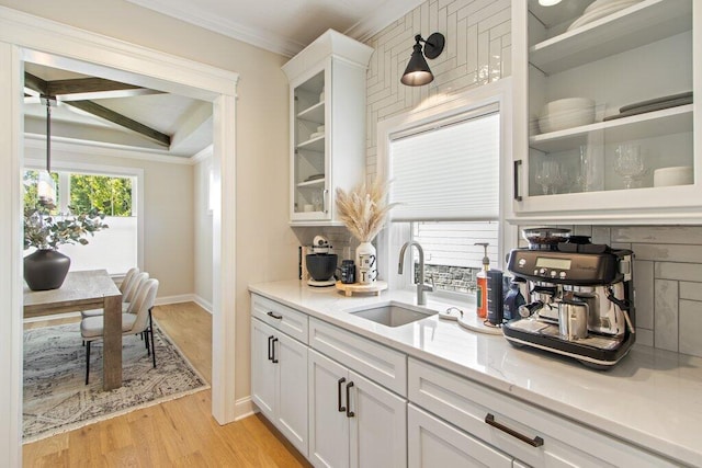 kitchen with sink, tasteful backsplash, crown molding, light hardwood / wood-style flooring, and white cabinets