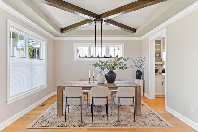 dining room featuring beam ceiling, plenty of natural light, and light hardwood / wood-style floors