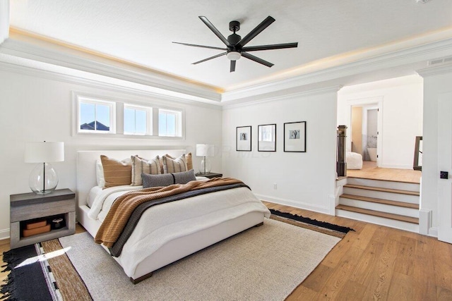 bedroom with hardwood / wood-style flooring, crown molding, ceiling fan, and a tray ceiling