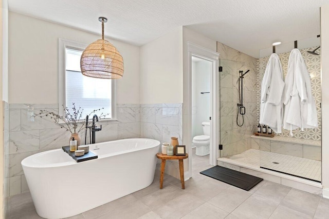 bathroom featuring plus walk in shower, tile walls, a textured ceiling, and toilet