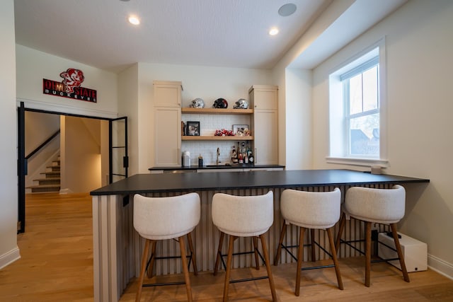 bar with sink, backsplash, and light wood-type flooring