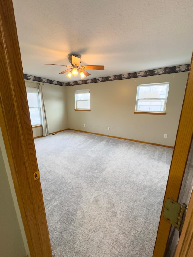 carpeted empty room featuring ceiling fan and a textured ceiling