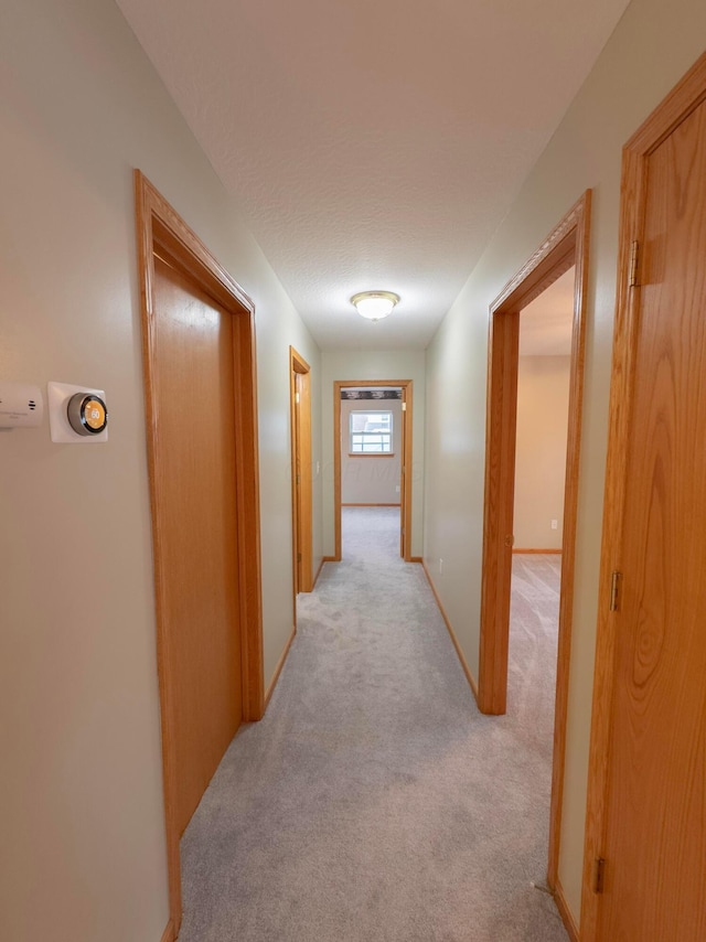 corridor featuring light carpet and a textured ceiling