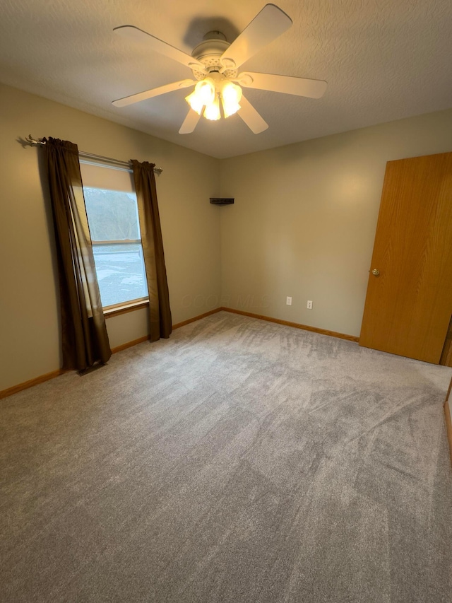 carpeted spare room with ceiling fan and a textured ceiling