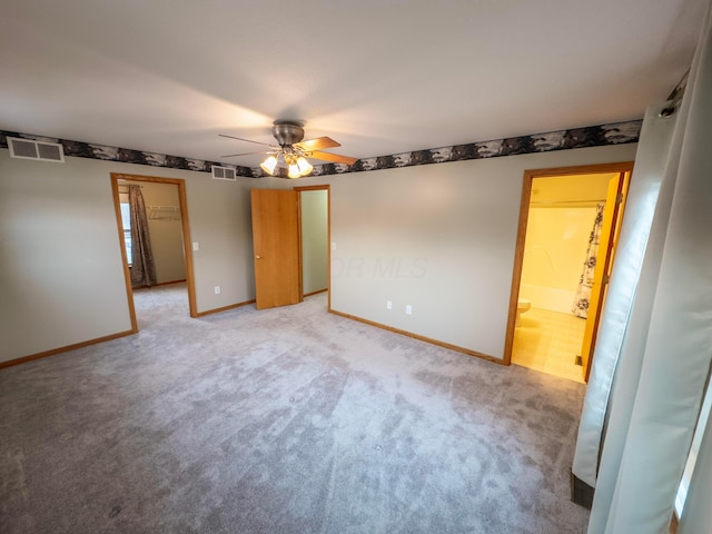 unfurnished bedroom with ensuite bath, light colored carpet, and ceiling fan