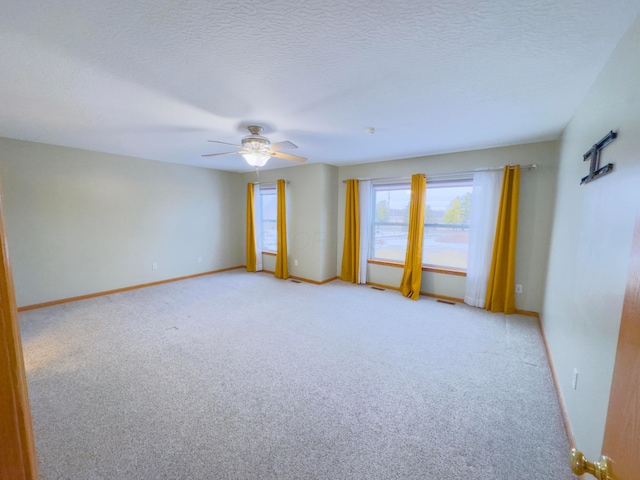 spare room featuring ceiling fan, light colored carpet, and a textured ceiling