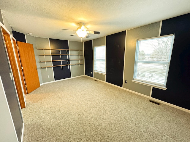 unfurnished room with ceiling fan, light colored carpet, and a textured ceiling