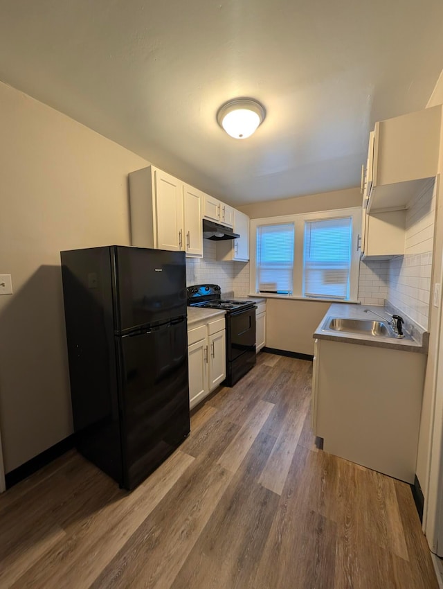 kitchen with sink, dark wood-type flooring, white cabinetry, backsplash, and black appliances