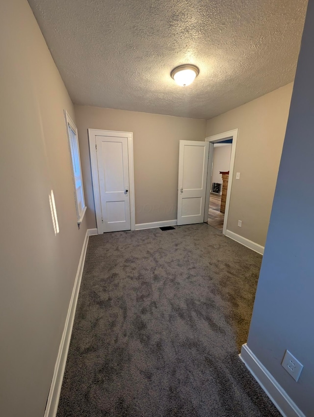 interior space featuring dark carpet and a textured ceiling