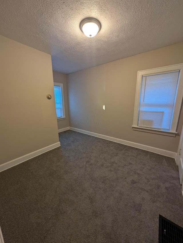 carpeted empty room with a textured ceiling