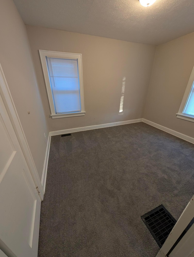 carpeted empty room featuring a textured ceiling