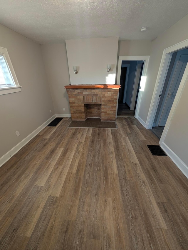 unfurnished living room featuring a textured ceiling, dark hardwood / wood-style flooring, and a fireplace