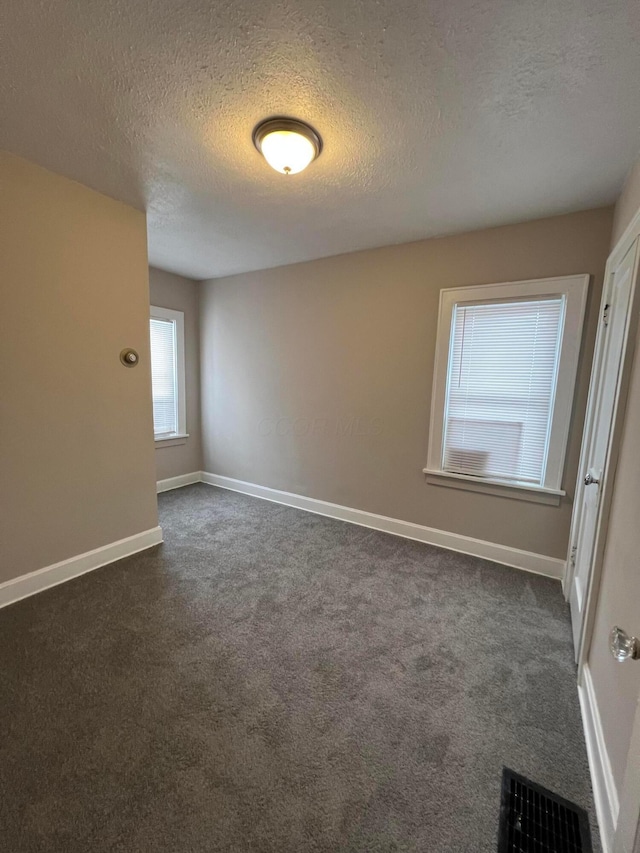 carpeted spare room with a textured ceiling