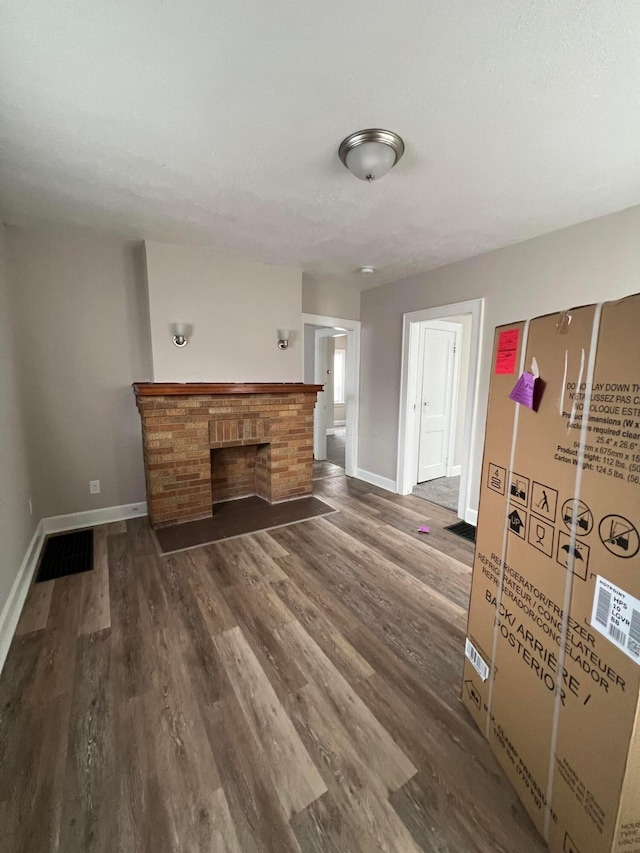 unfurnished living room featuring a brick fireplace and dark hardwood / wood-style floors