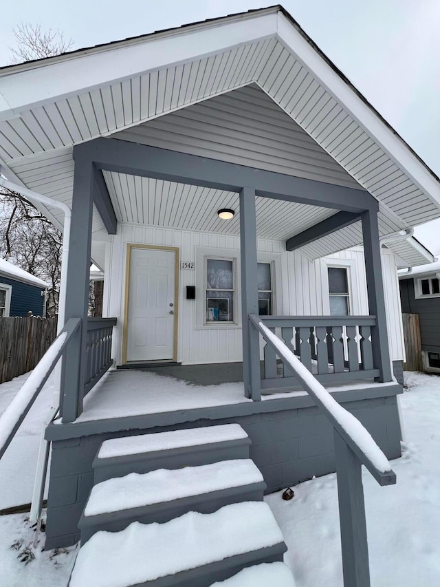 snow covered property entrance featuring a porch