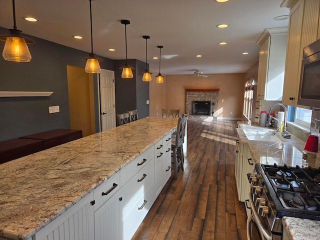 kitchen with a kitchen island, decorative light fixtures, white cabinetry, sink, and stainless steel appliances